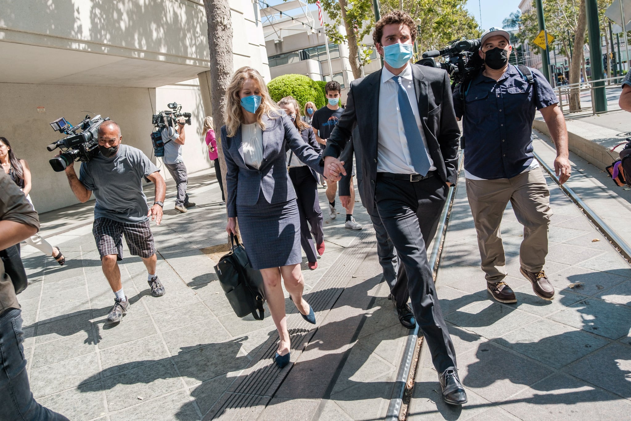 Elizabeth Holmes (C), founder and former CEO of blood testing and life sciences company Theranos, leaves the courthouse with her husband Billy Evans after the first day of her fraud trial in San Jose, California on September 8, 2021. - California jurors tasked with deciding whether fallen biotech star Elizabeth Holmes is guilty of a stunning fraud or is herself a victim were set to hear opening arguments in her trial on September 8, 2021. Federal prosecutors in the heart of Silicon Valley have in their filings portrayed Holmes as a villain who swindled investors in the diagnostics company Theranos -- which she founded at age 19 -- with tests that did not work. (Photo by Nick Otto / AFP) (Photo by NICK OTTO/AFP via Getty Images)